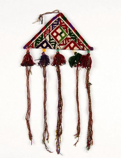 Amulet van textiel met patronen en kwastjes versierd