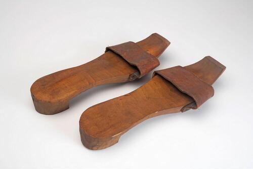 Een paar houten slippers met leren band