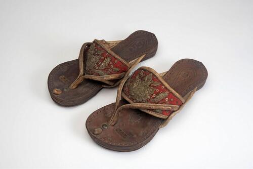 Een paar leren slippers met geborduurde flanel band