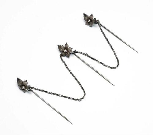 Drie door zilveren een ketting aan elkaar verbonden kabajaspelden