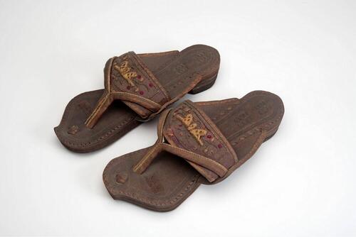 Een paar leren slippers met geborduurde flanel band