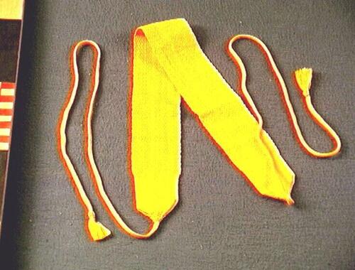 Een oranje katoenen gordel, onderdeel van een set kleding voor een monnik.