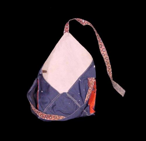 Tas van blauw katoen met draagband van rode wollen stof