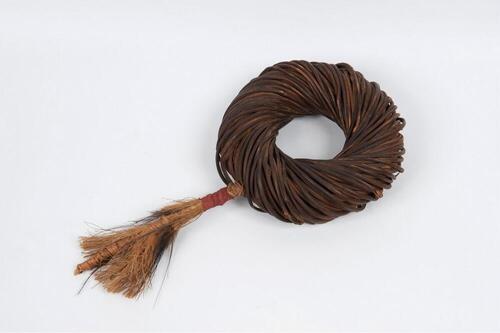 Bovenarmband van gevlochten rotan met pluim van Casuarisveren.