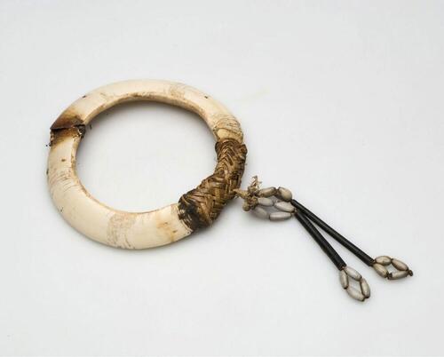 Armband van twee varkensslagtanden, met vlechtwerk en hars verbonden en versierd met jobstranen