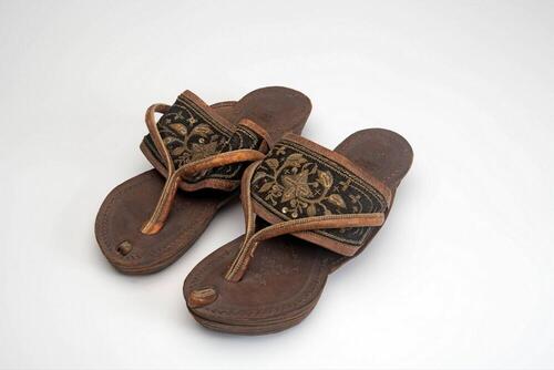 Een paar leren slippers met geborduurde flanel band