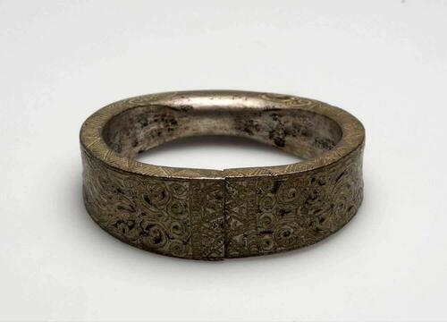 Metalen armband versierd met ciseleerwerk, onderdeel van een paar