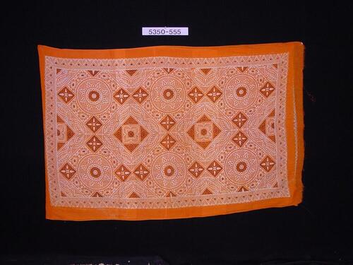 Oranje hoofddoek met bedrukte ornamenten van cirkels en ruiten waarbinnen figuren
