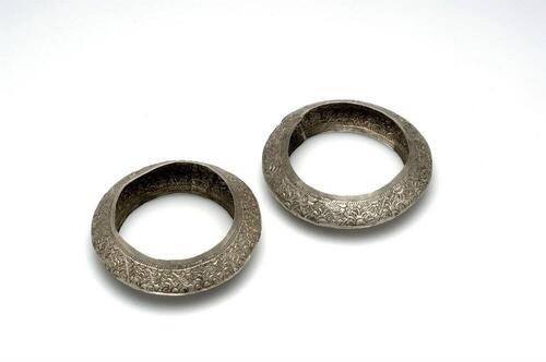 Paar zilveren armbanden, versierd met gedreven geometrische figuren, gedragen door jonge meisjes