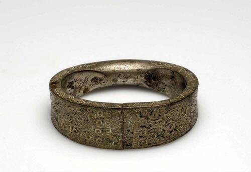 Metalen armband versierd met ciseleerwerk, onderdeel van een paar