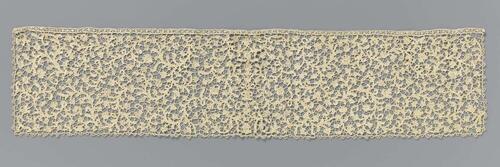Dasslip van naaldkant met een symmetrisch patroon van vele ranken met kleine bladeren en bloemen