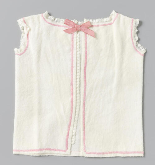 Babyhemd van witte flanel met een rand in roze flanelsteek en roze lint; in de armsgaten versierd…
