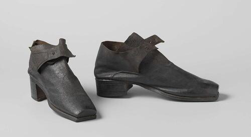 Schoenen van zwart leer met een afgeplatte, vierkante neus, een hoog voorblad waarover twee…